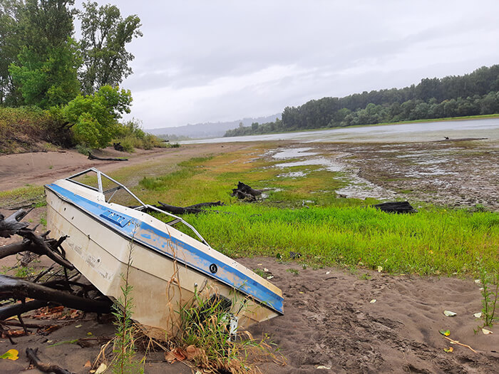 Beached recreational boat on land above waterway